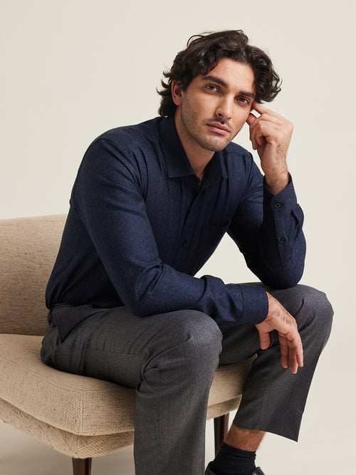 L’homme porte une chemise en flanelle mérinos Wolk de couleur marine mélangée sur un pantalon gris